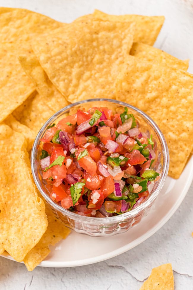 bowl of fresh Pico de Gallo on a plate with tortilla chips