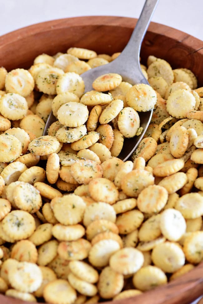 seasoned oyster crackers in a wood bowl with a serving spoon