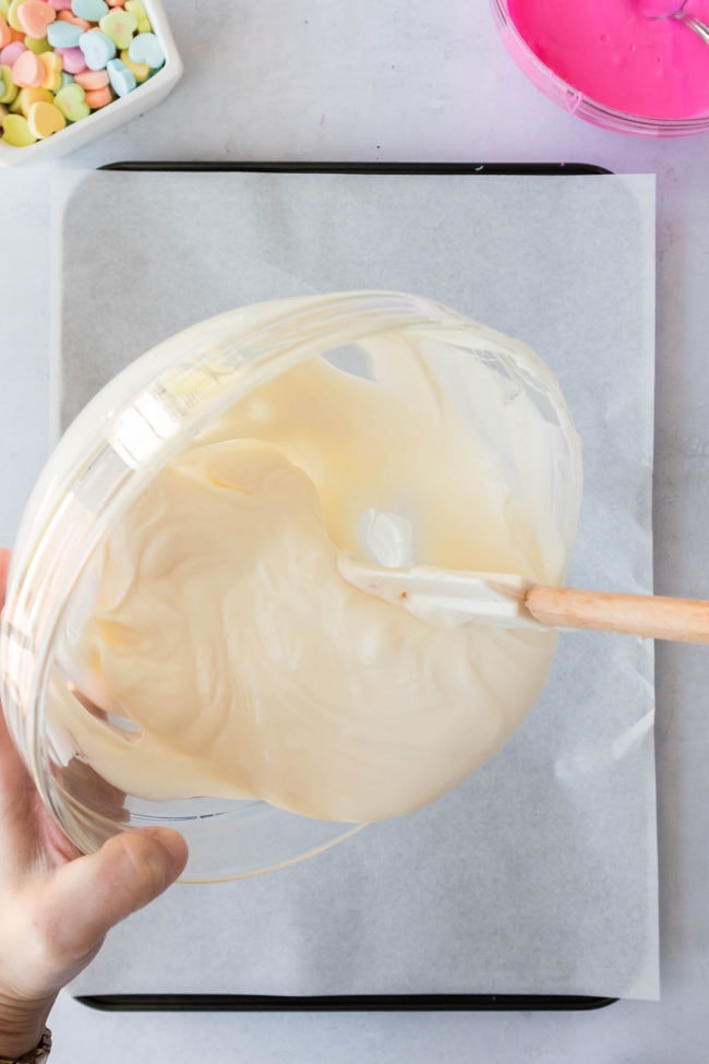 pouring melted white chocolate onto a pan