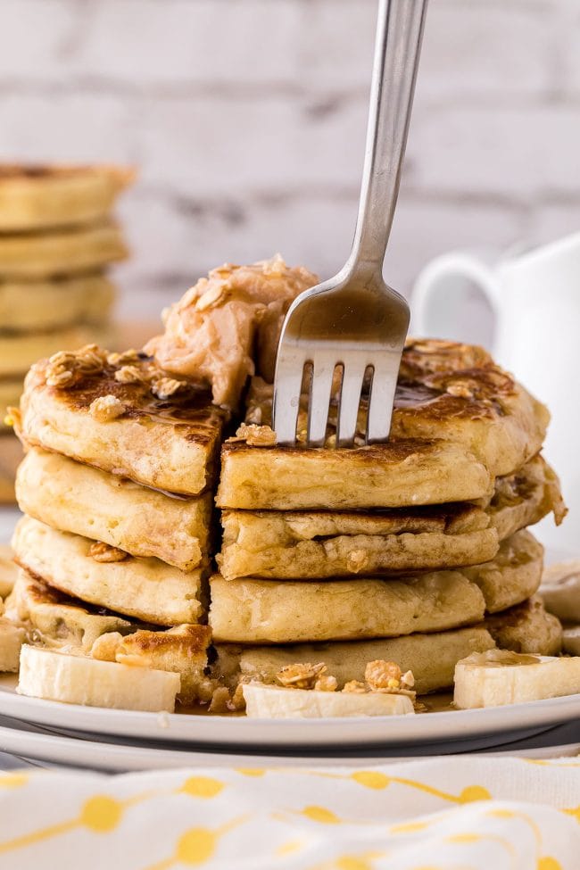 fork going into a stack of Banana Pancakes With Granola Crunch