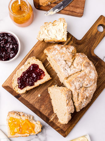 round loaf of bread with pieces cut and spread with jam