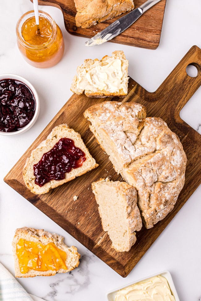 round loaf of bread with pieces cut and spread with jam