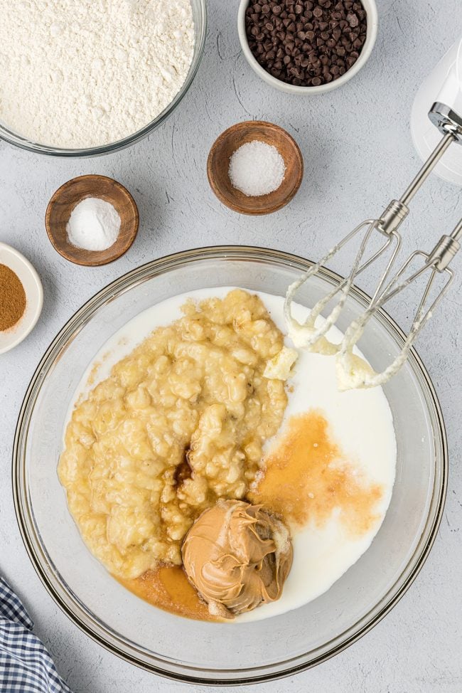 ripe bananas in a bowl with quick bread batter and electric mixer