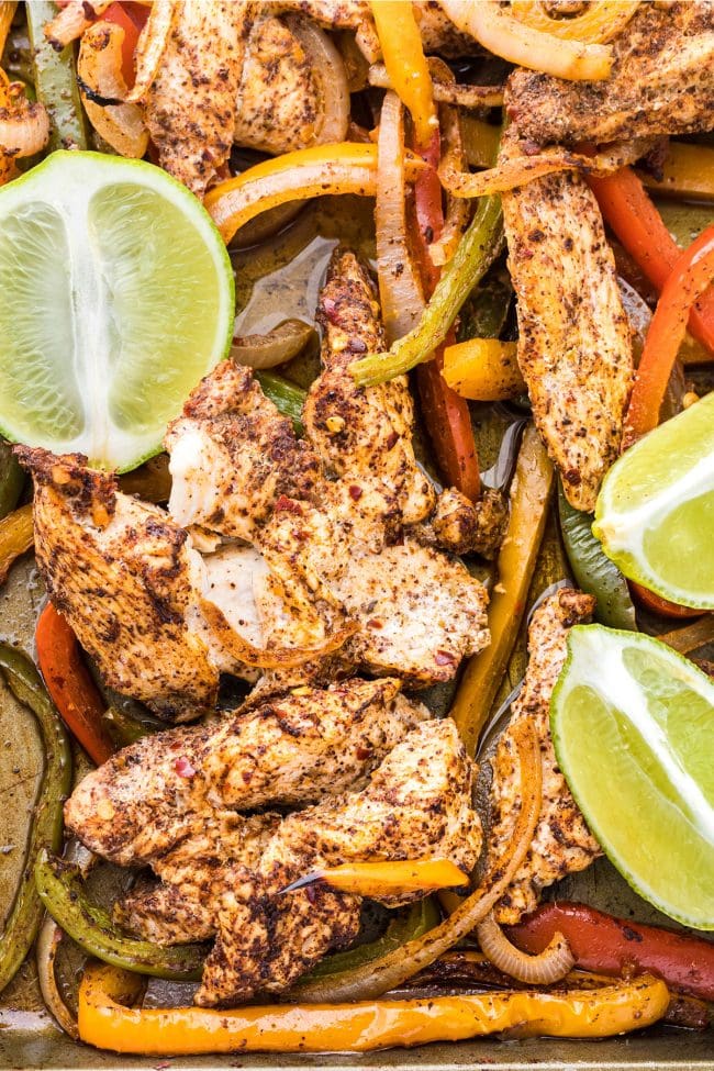 oven fajitas with chicken and lime garnish on a sheet pan