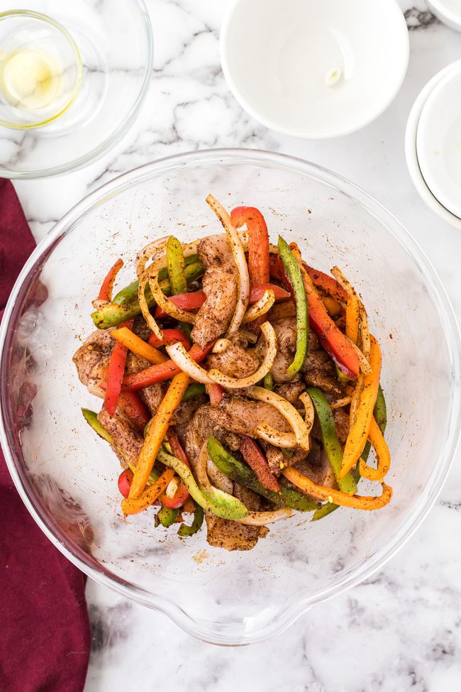 chicken and veggies in a glass bowl with fajita seasonings