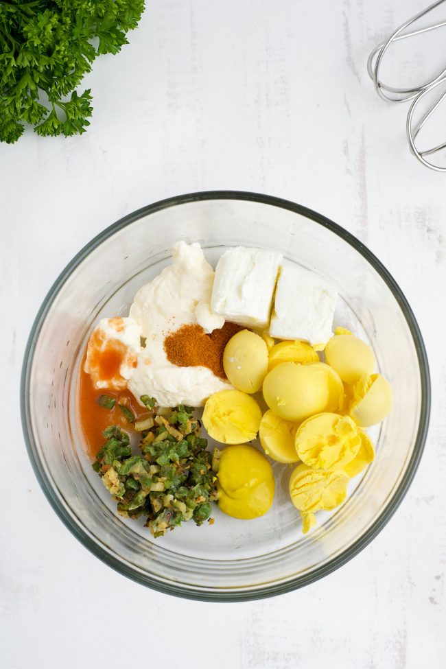 spicy deviled eggs filling in a glass mixing bowl