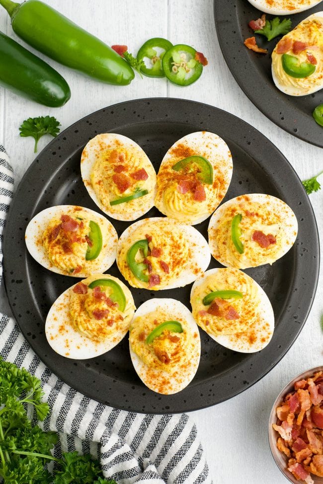 deviled eggs on a round platter with jalapenos