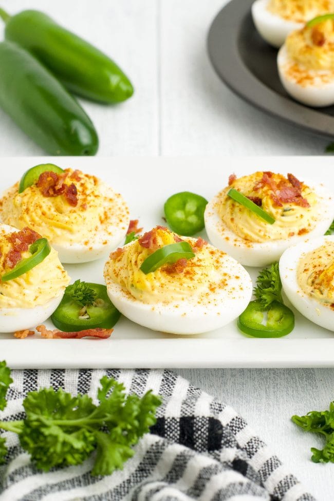 white tray with deviled eggs topped with jalapeno slices