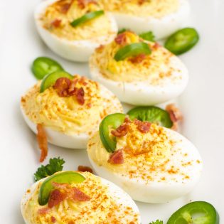 tray of deviled eggs topped with jalapeno slices