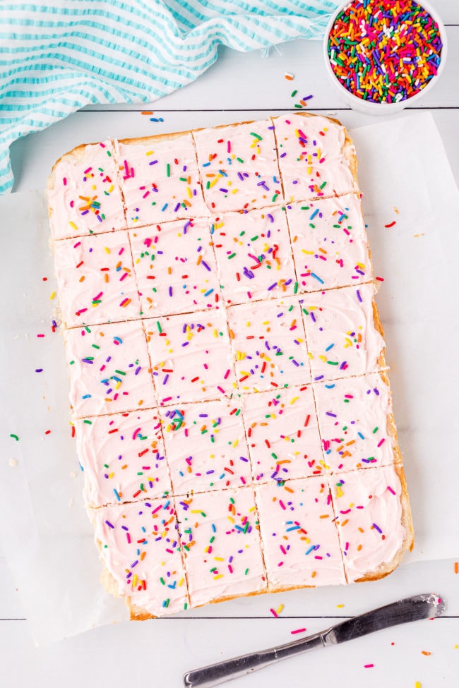 sugar cookie bars with pink frosting and sprinkles cut into servings