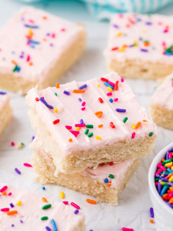 stack of sugar cookie bars with pink buttercream and sprinkles