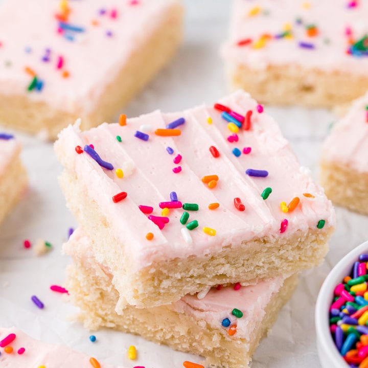 stack of sugar cookie bars with pink buttercream and sprinkles
