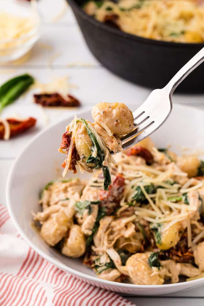 a bowl  and fork of creamy chicken gnocchi with sun dried tomatoes