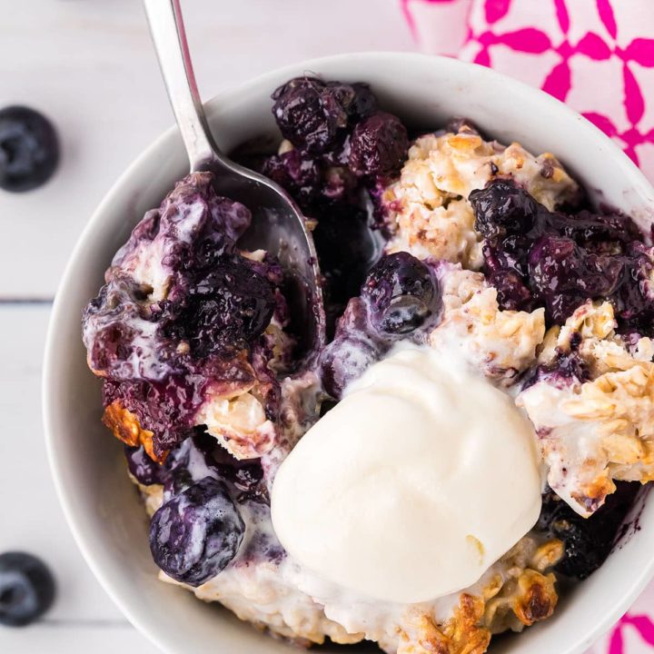 warm bowl of fruit crisp with oat topping and a scoop of ice cream