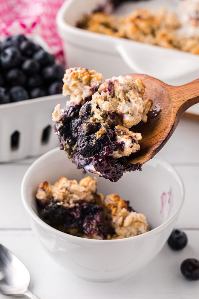 berry crisp on a large wooden spoon