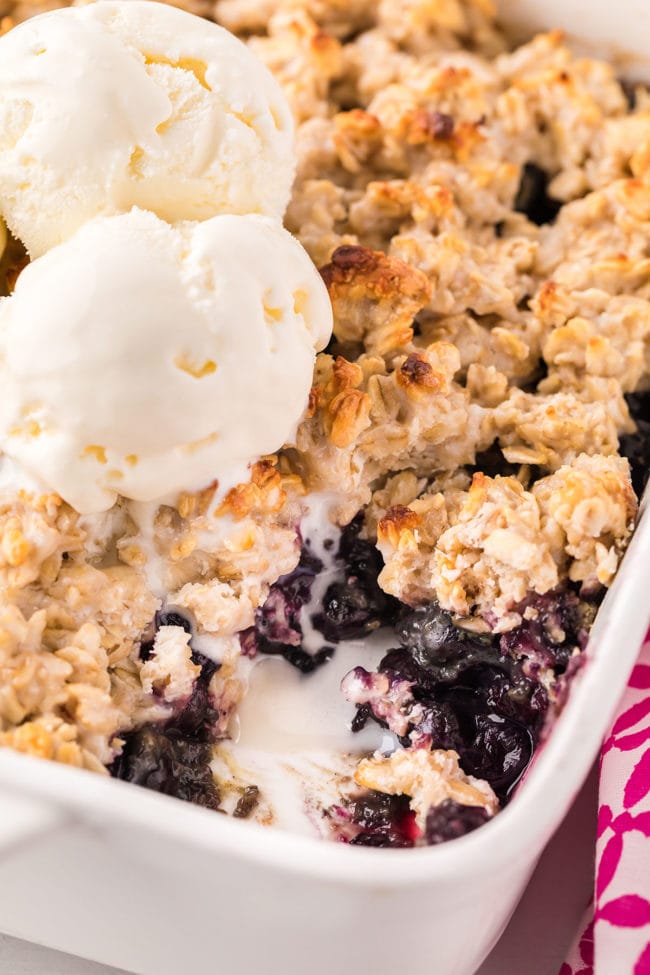 baking dish with warm blueberry crisp topped with vanilla ice cream