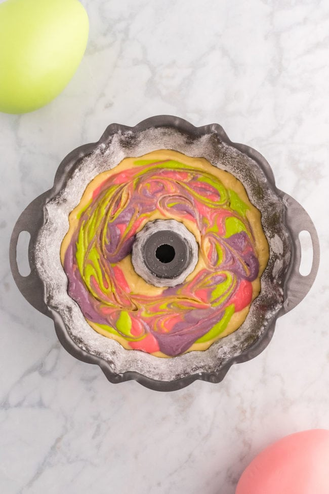 colorful cake batter swirled in bundt pan