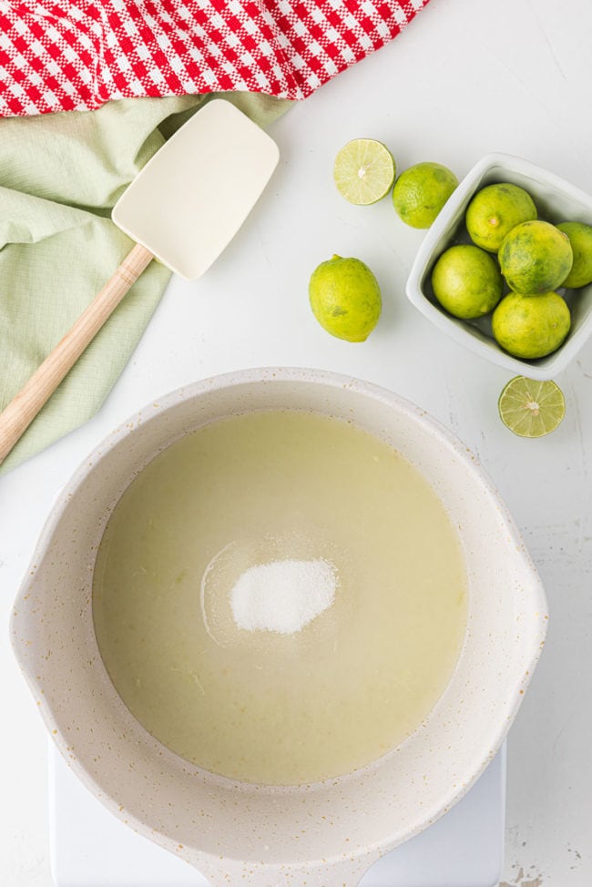 key lime syrup in a bowl with fresh limes on the counter