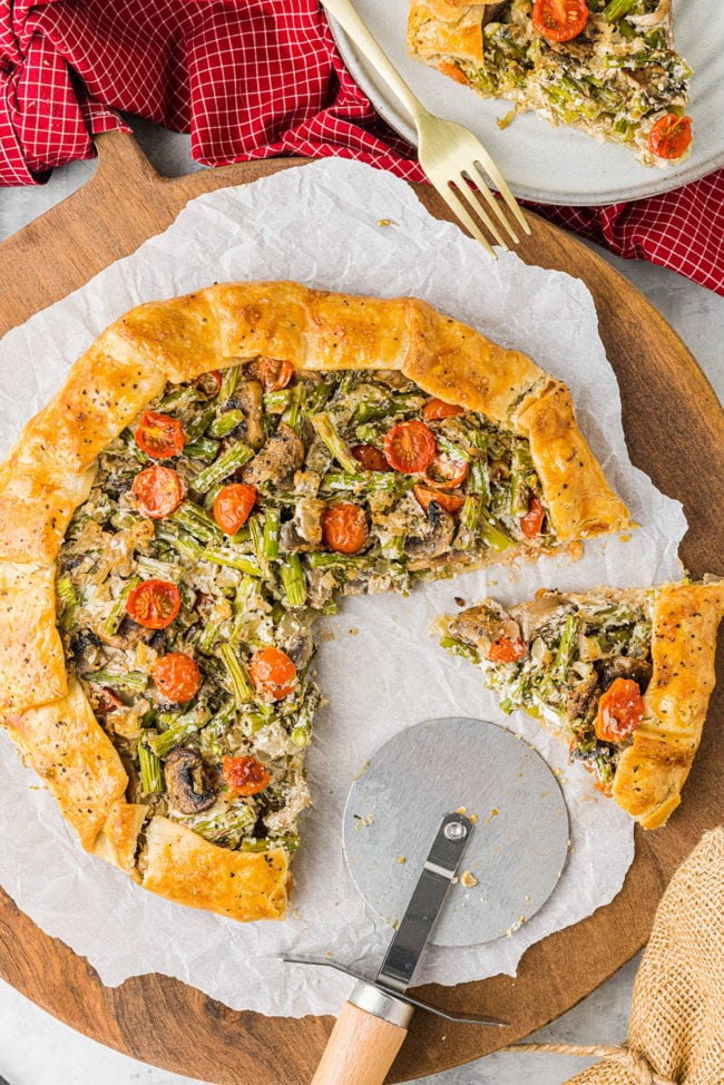 spring veggie savory galette with a pizza cutter to serve