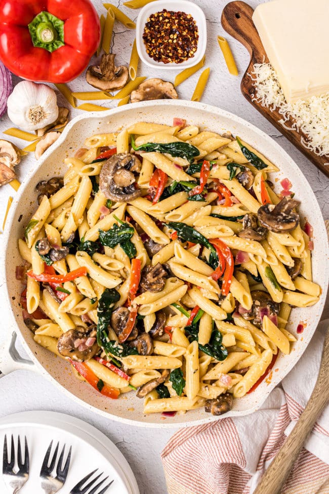 al dente pasta with baby spinach, red bell pepper, mushrooms and onions in a skillet
