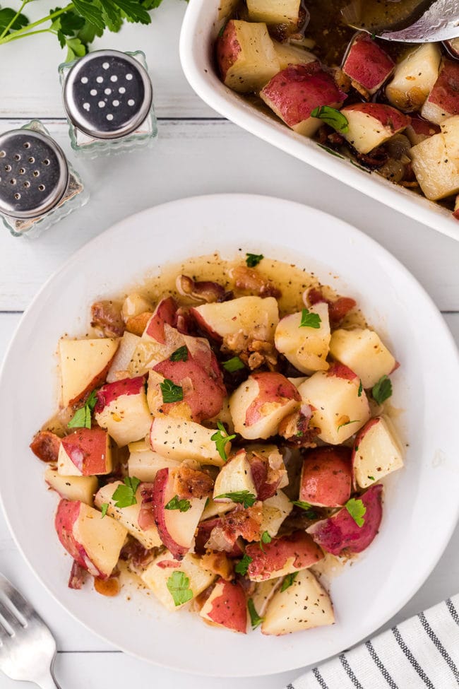 a white plate and baking dish with potato salad