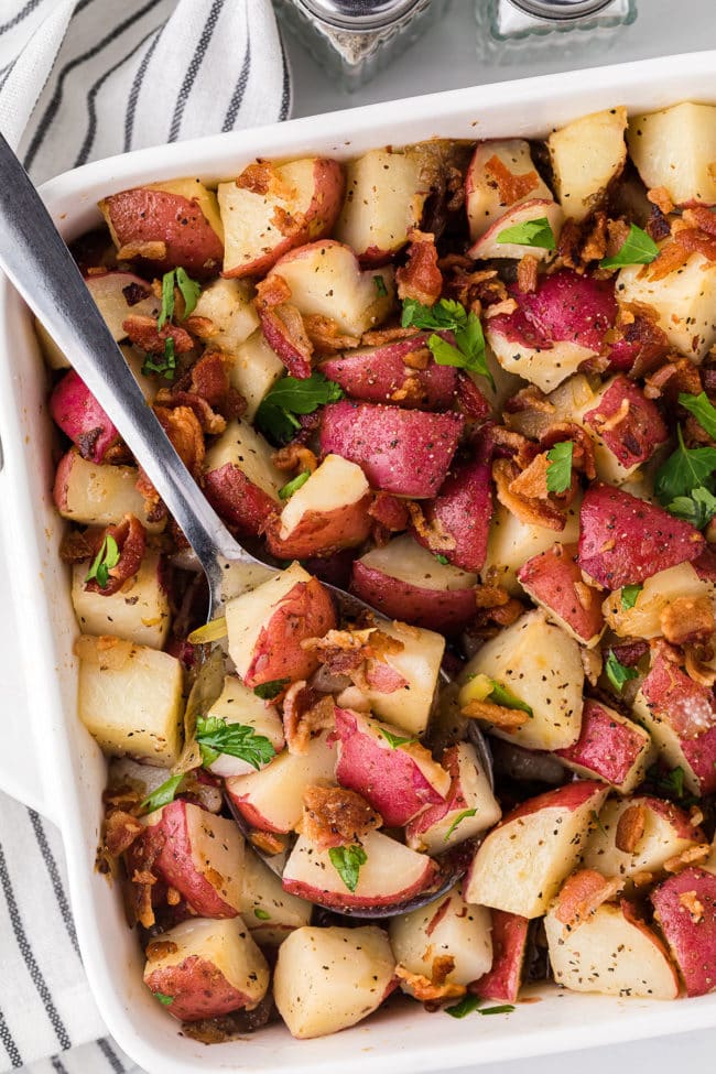 potato salad in a square baking dish with a serving spoon