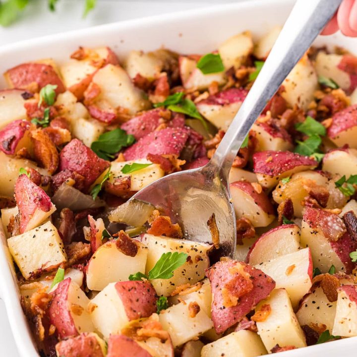 potato salad with red skinned potatoes in a baking dish with a serving spoon