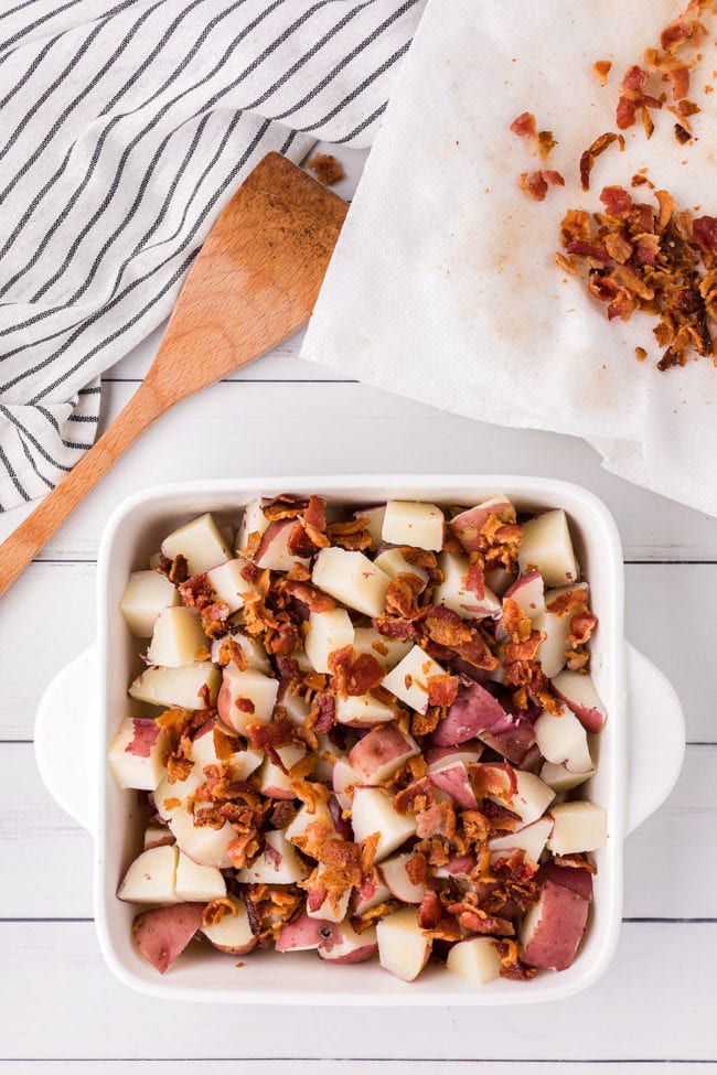 red skin potatoes and bacon crumbles in a white baking dish