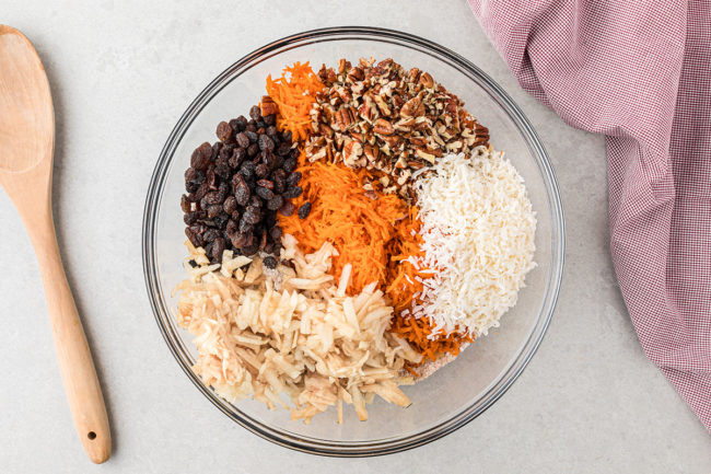 muffin ingredients in a glass mixing bowl with wooden spoon next to it