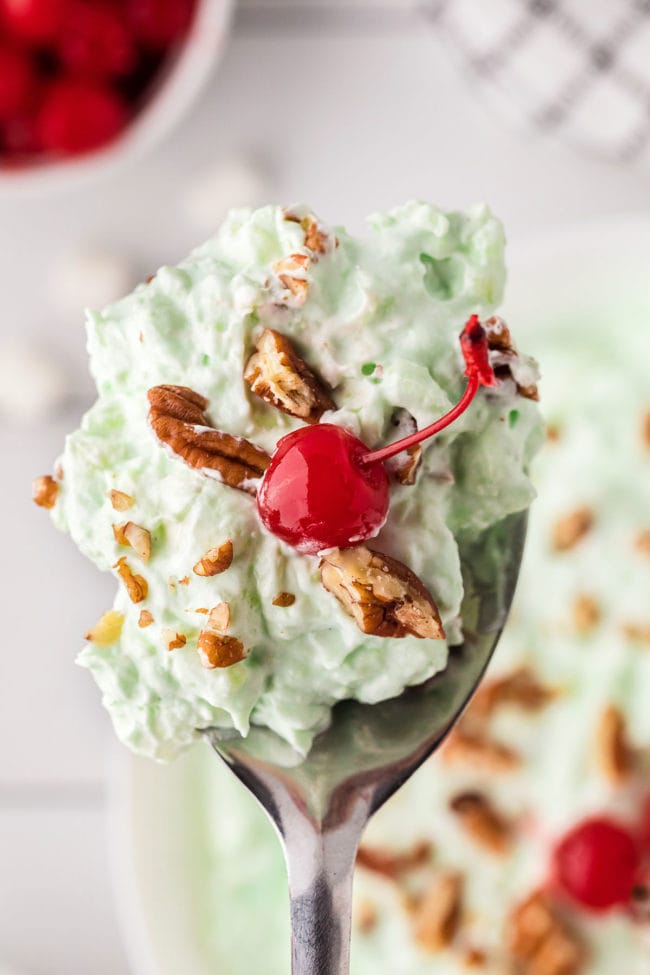 Pistachio fluff with a cherry on a spoon
