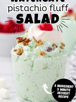 green fluff salad in a parfait cup with chopped nuts, whipped cream and cherries on top