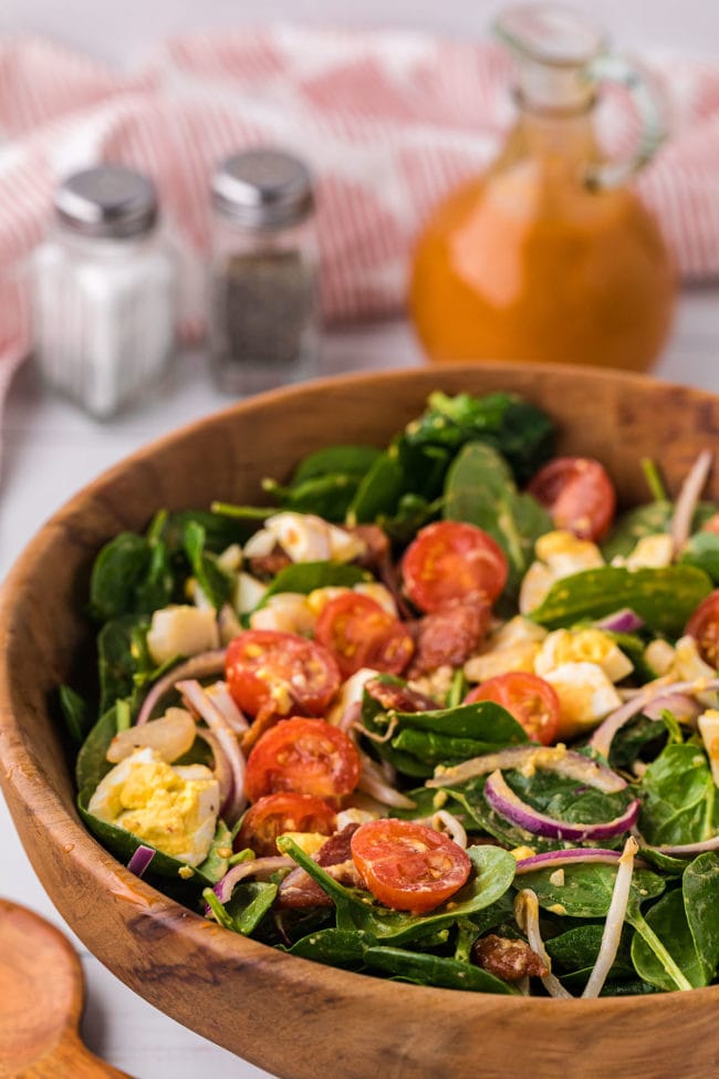 bowl of spinach salad with a bottle of homemade dressing in background