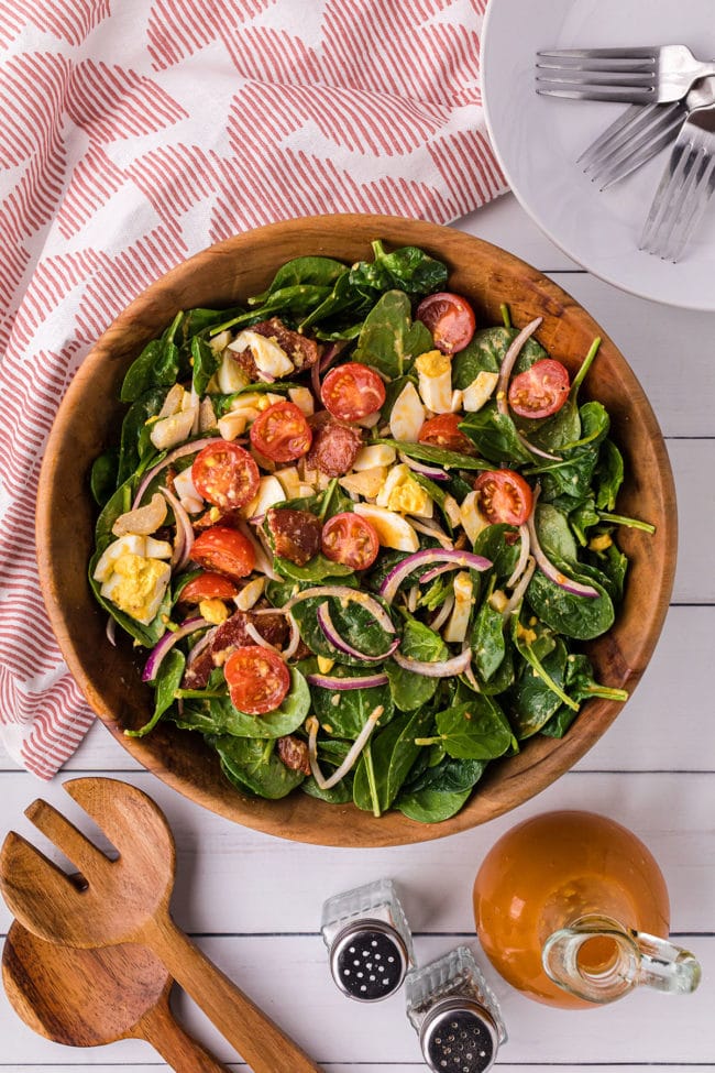 overhead shot of salad with red and white towel and wooden fork and spoon