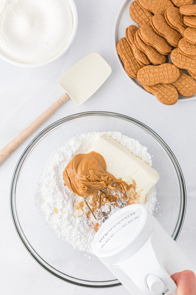 Mixing cream cheese, powdered sugar and peanut butter in a glass bowl step 1