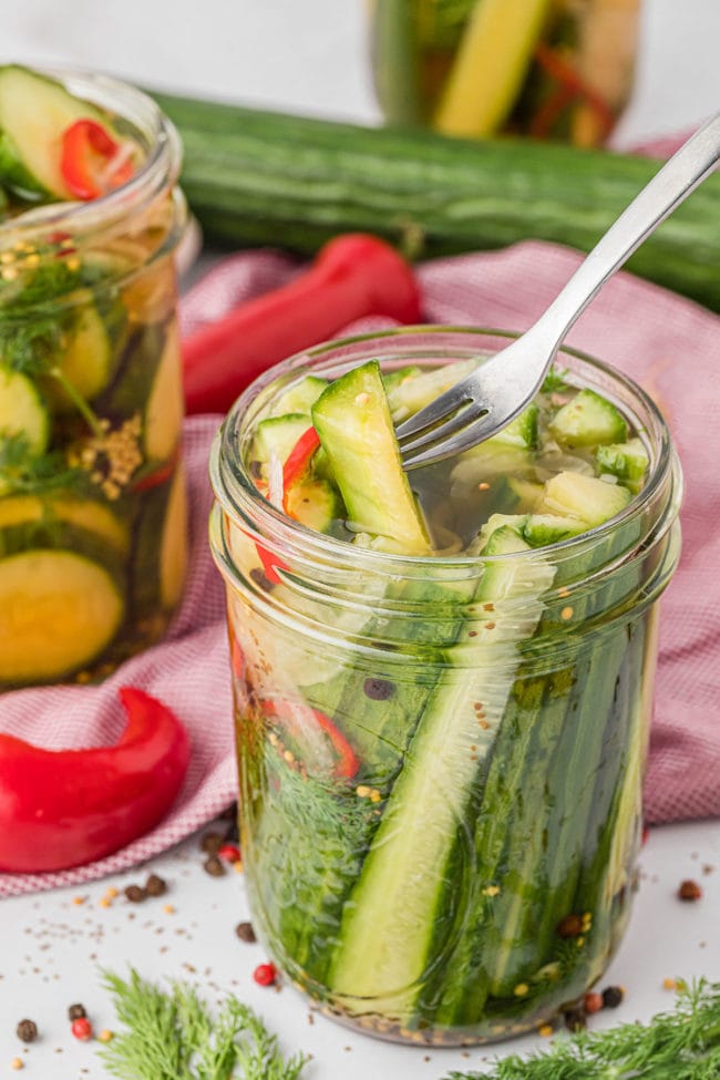 a fork pulling a pick spear out of a jar of homemade refrigerator pickles