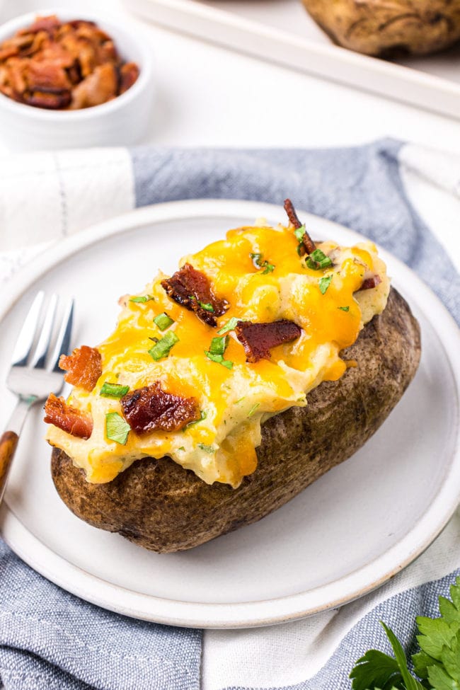 plate with fork and a stuffed baked potato topped with bacon