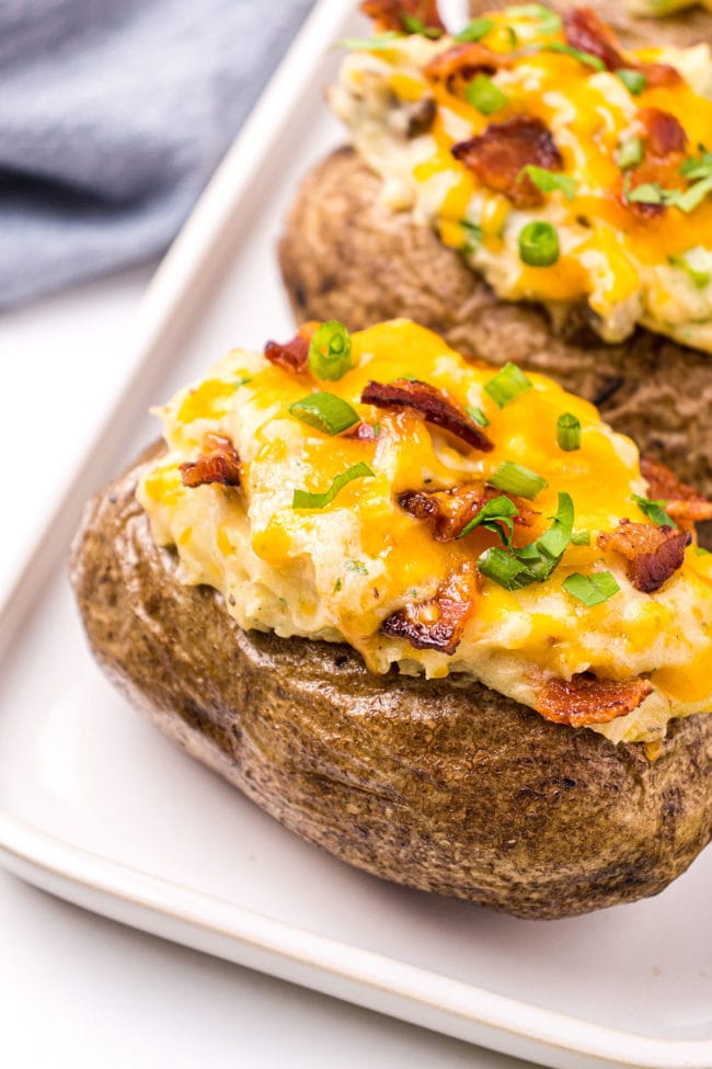 cheesy twice baked potatoes on a white tray