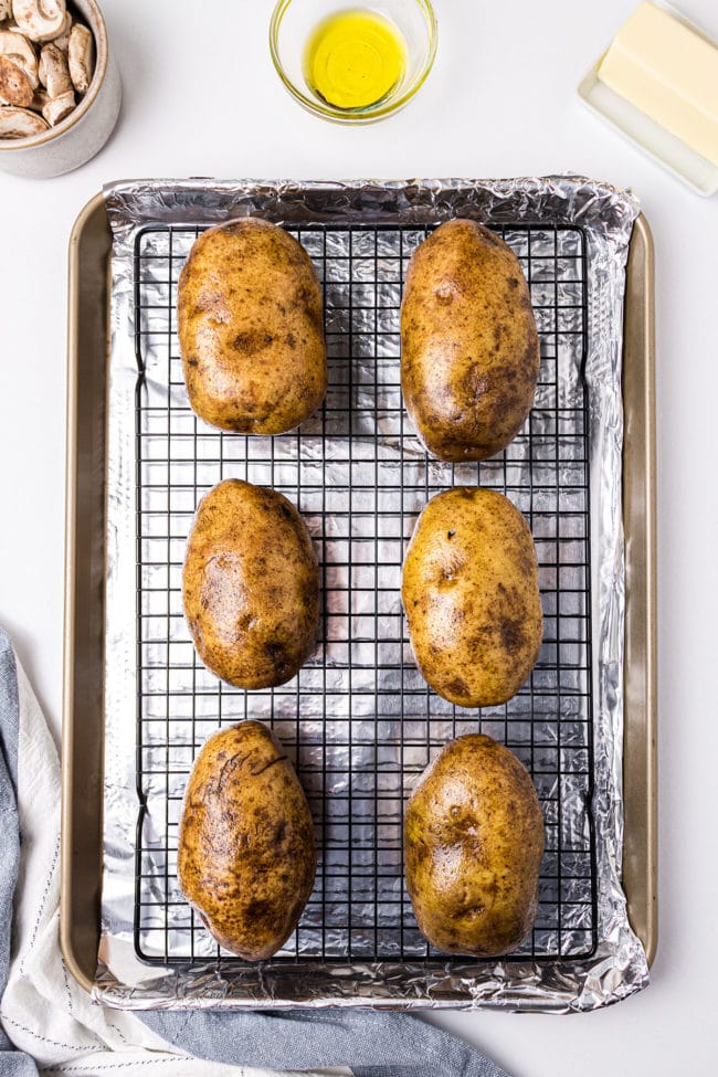 potatoes on a cooling rack on a sheet pan ready to go in the oven