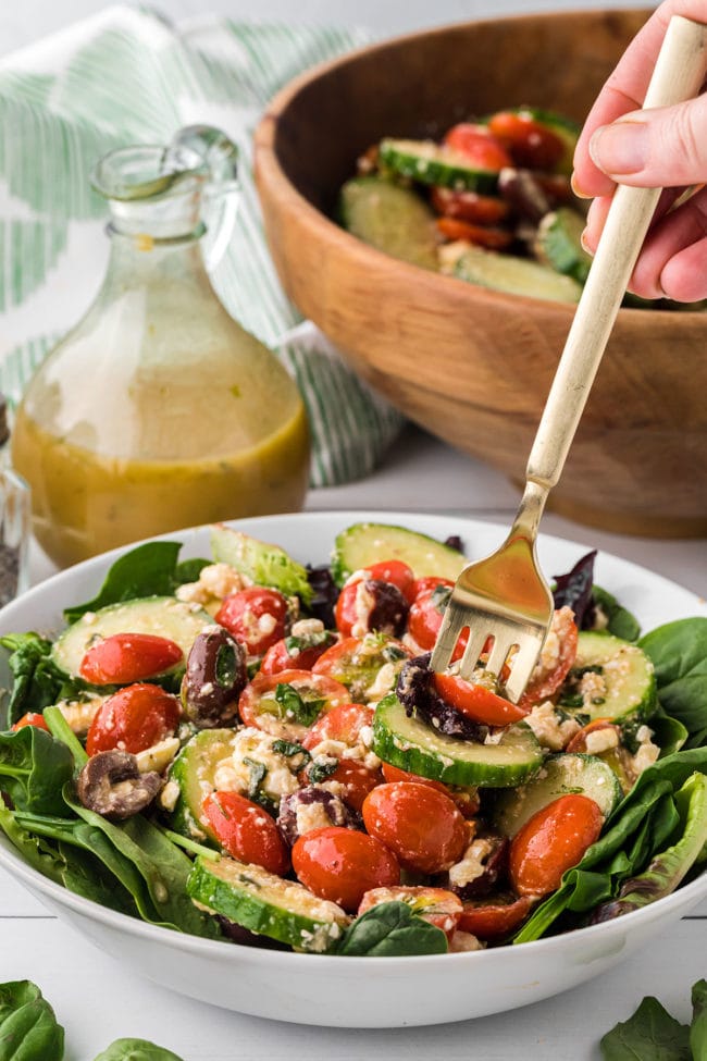 bowl of tomato cucumber feta salad with a fork in the salad