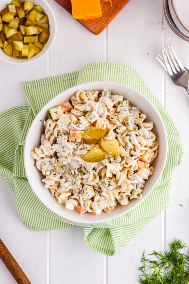 Dill pickle pasta salad in a white bowl with a green towel