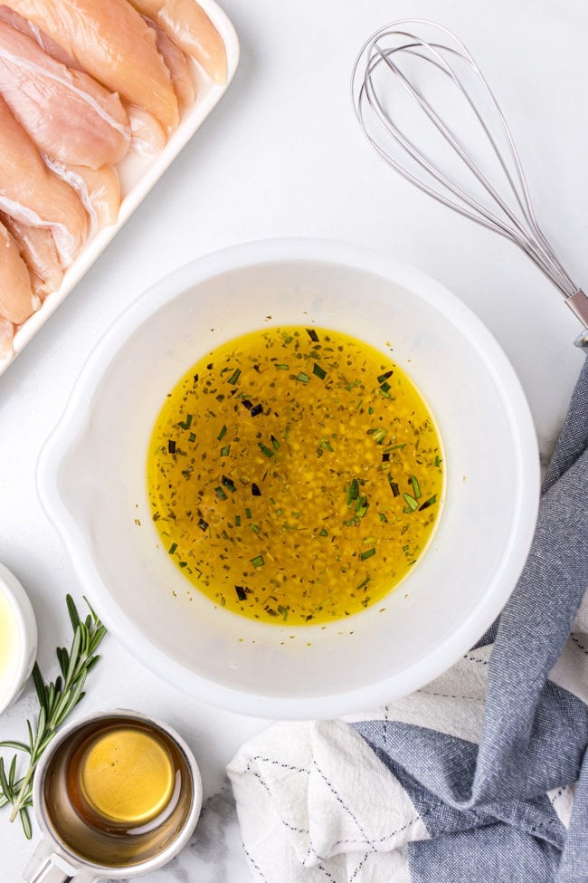 lemon garlic and fresh herb marinade for grilled chicken in a white bowl