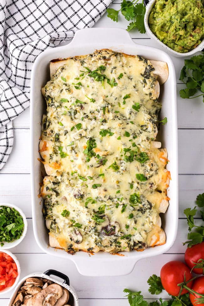 homemade chicken enchiladas casserole in a white baking dish