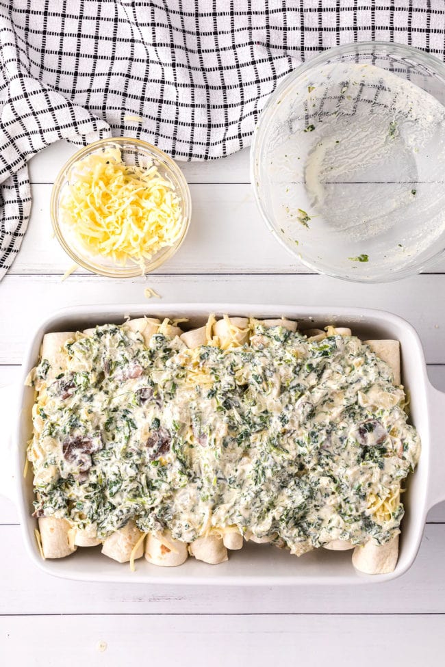 chicken and spinach enchiladas with white sauce in a casserole dish