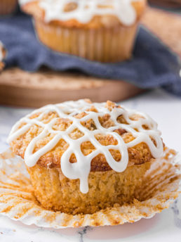 orange muffin with icing and paper pulled back
