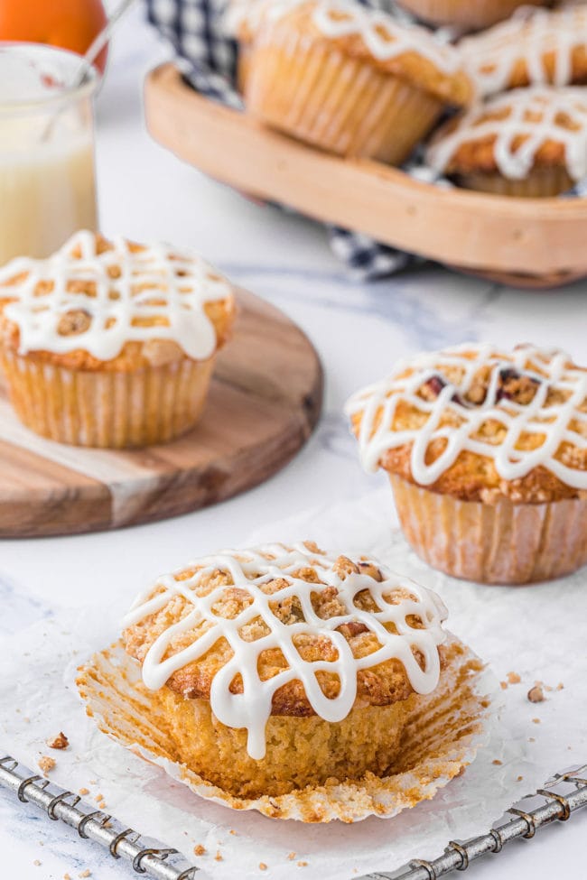 orange muffins with icing on a cooling rack with parchment paper