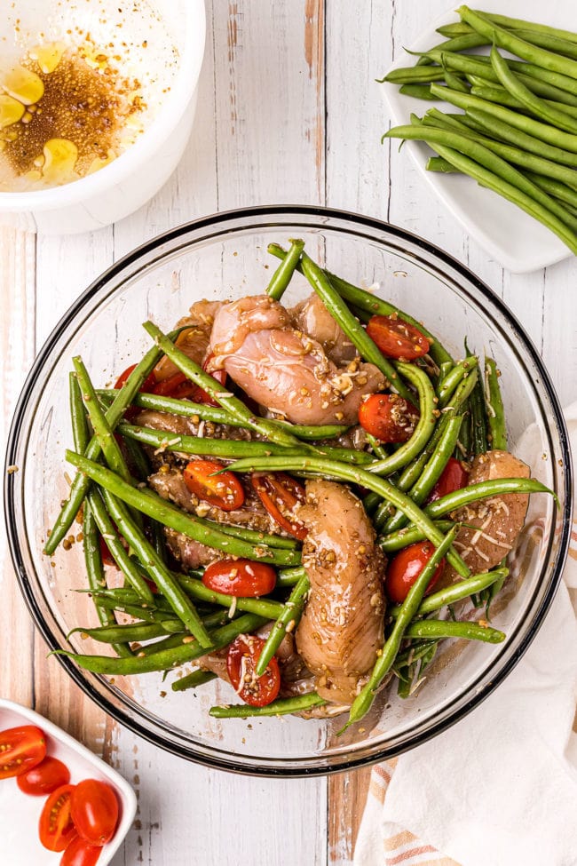 chicken tenders, green beans and tomatoes in a glass bowl