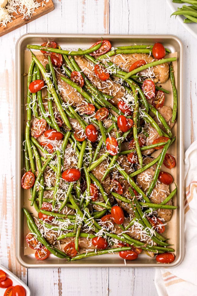 sheet pan dinner with chicken tenders, green beans and tomatoes ready for the oven.