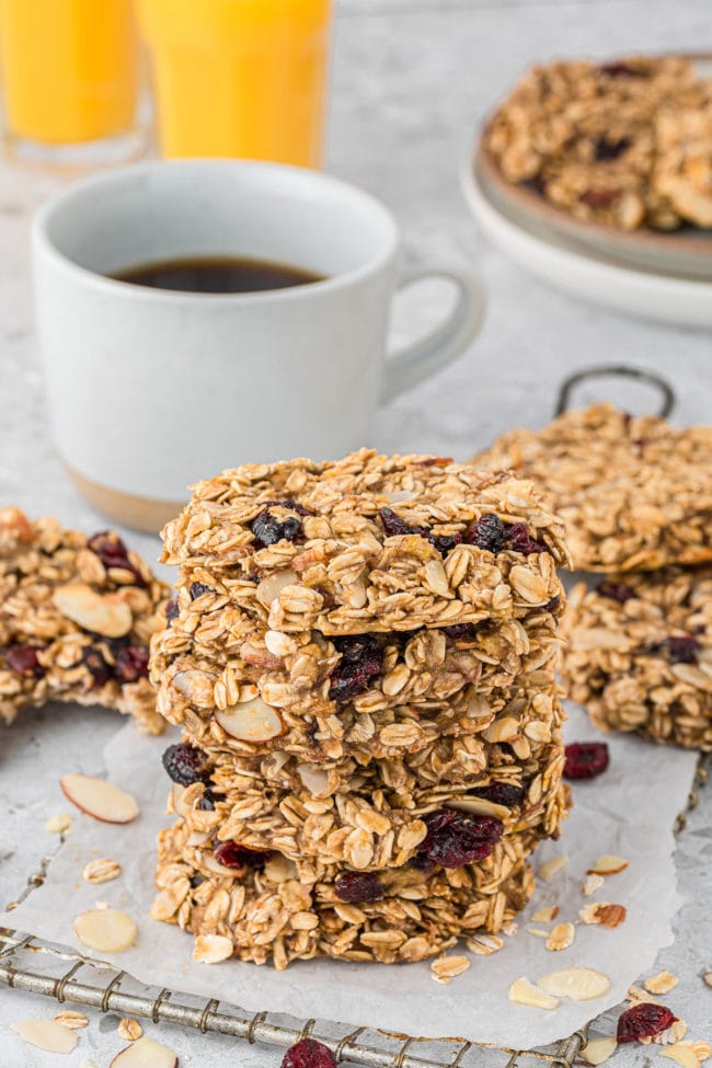 a stack of cookies with a cup of coffee and glasses of orange juice in the background