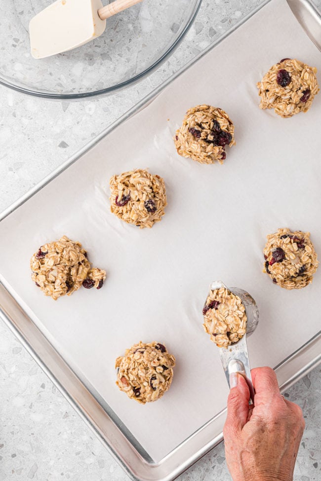 scooping out cookie dough with 1/4 cup measure and placing them on a baking sheet