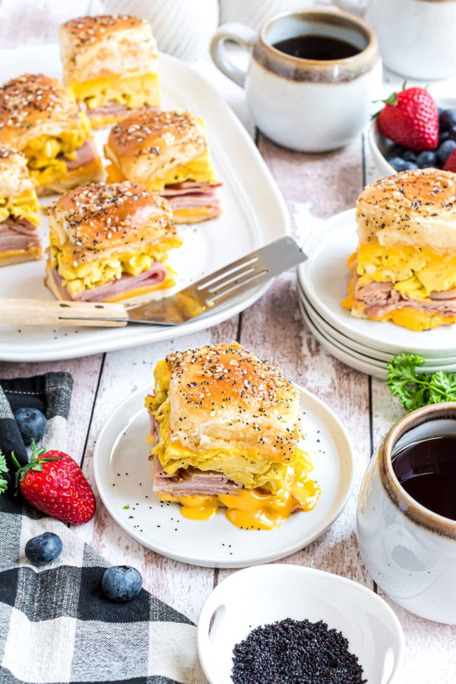 breakfast sandwiches on a table with coffee and fruit
